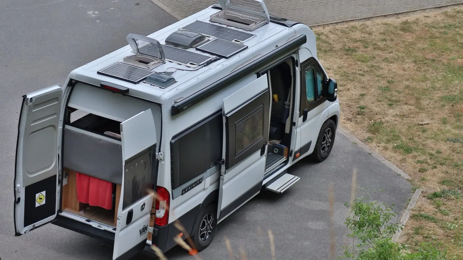 Camper mit Solarmodulen auf dem Dach an einem Stellplatz im Grünen