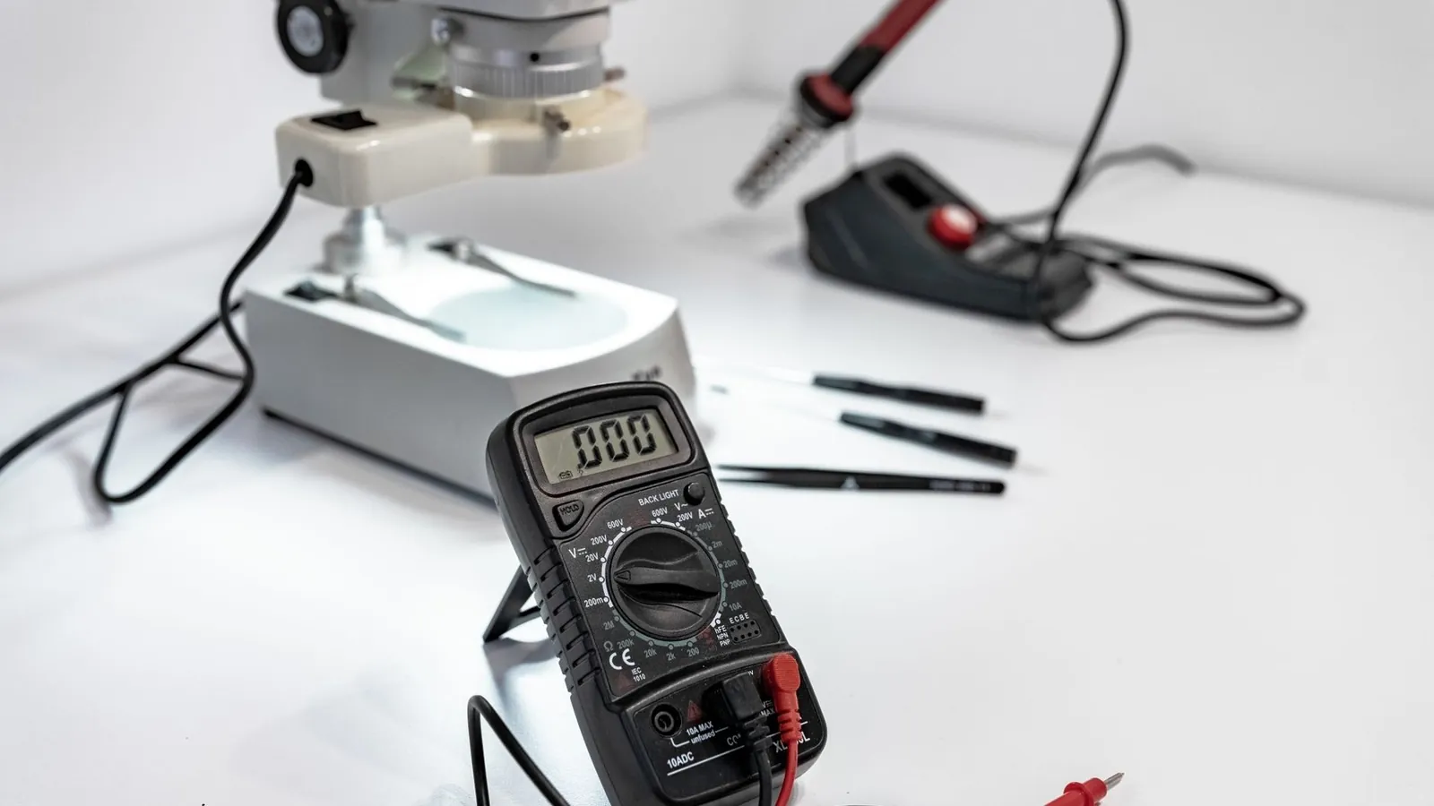 Multimeter mit roter und schwarzer Messspitze an den Polen einer Autobatterie